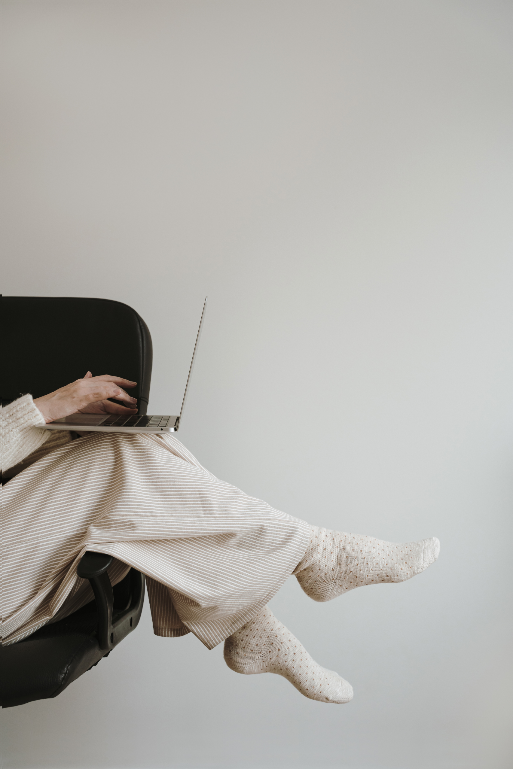 Woman sitting in a chair using a laptop with neutral cozy outfit, representing Amazon Storefront Isn't Converting and optimizing affiliate strategy for better conversions